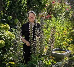 Jennifer Arnott in her garden, with Acanthus blooming in front of her